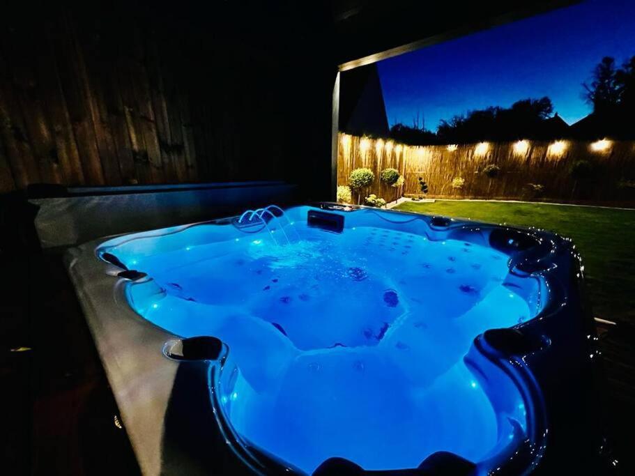una vasca idromassaggio blu in un cortile di notte di KosyHouse - Un petit coin de paradis-SPA & Massage a Cauffry