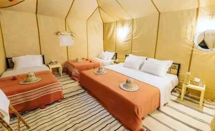a room with two beds in a tent at Maria Sahara Camp in Merzouga