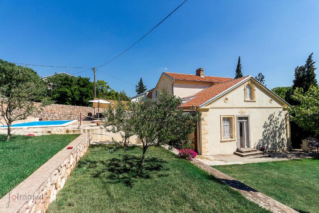 a small white house with a yard and a pool at Holiday home Villa Mare in Novi Vinodolski