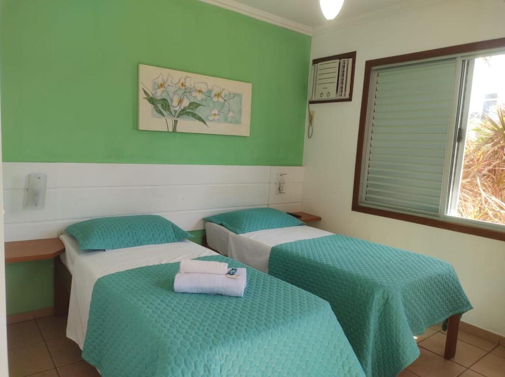 2 camas en una habitación con paredes verdes en Kata Hotel Boutique Floripa, en Florianópolis