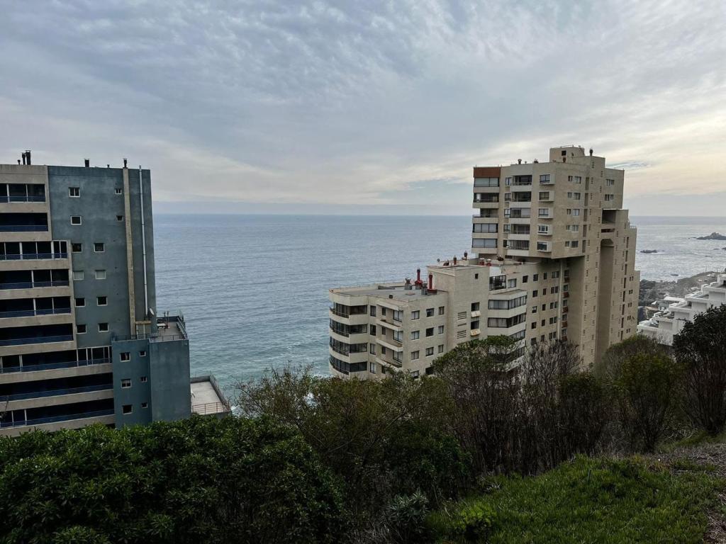uitzicht op twee hoge gebouwen en de oceaan bij Reñaca departamento in Viña del Mar