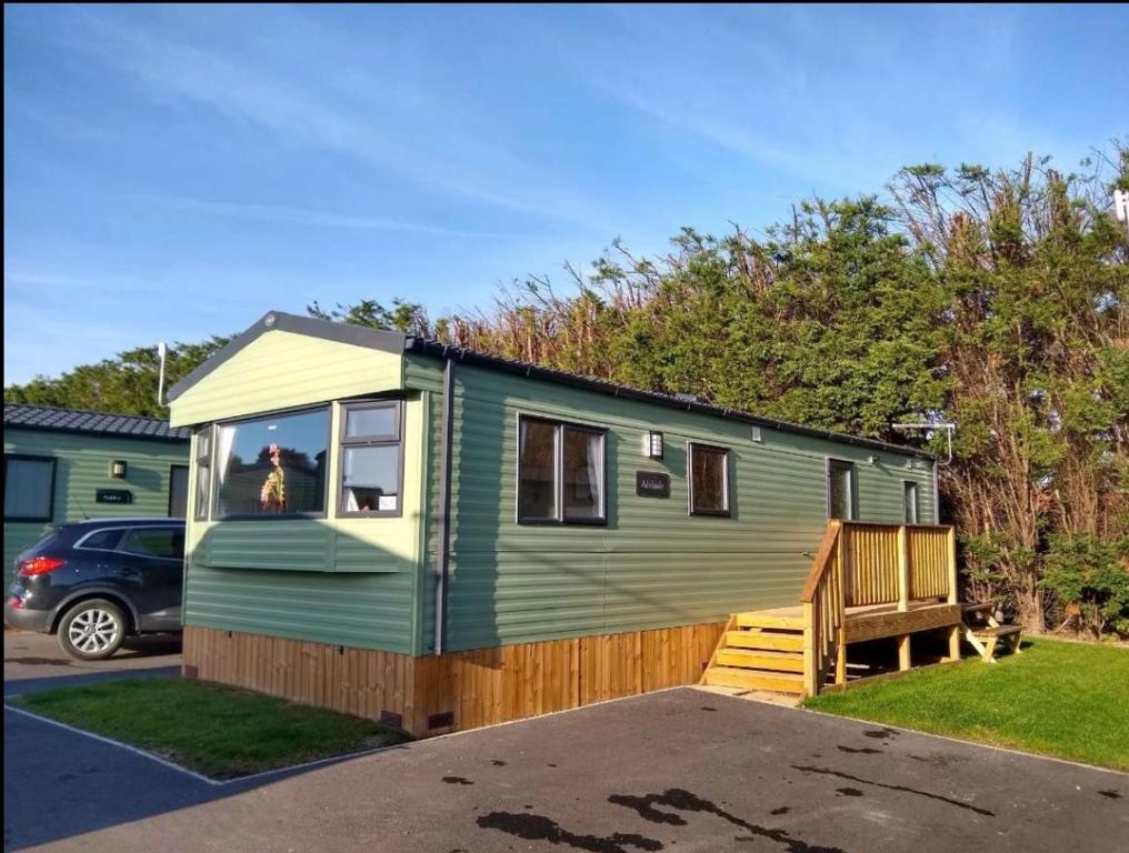 a green tiny house is parked in a driveway at Appleblossom Lodge, Lido Leisure Park, Knaresborough in Knaresborough