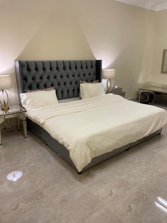 1 dormitorio con 1 cama grande y cabecero negro en شقة فندقية ثلاث غرف نوم وغرفة معيشة ومطبخ ومدخل خاص وباركنج سيارة en Riyadh Al Khabra