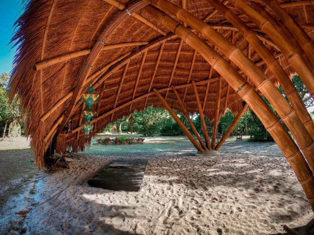 a large straw pavilion on a beach with at Namastê Pousada e Camping in Cananéia