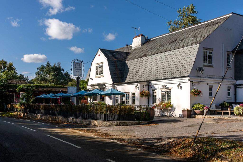 biały budynek z niebieskimi parasolami obok ulicy w obiekcie The Carpenters Arms w mieście Tonbridge