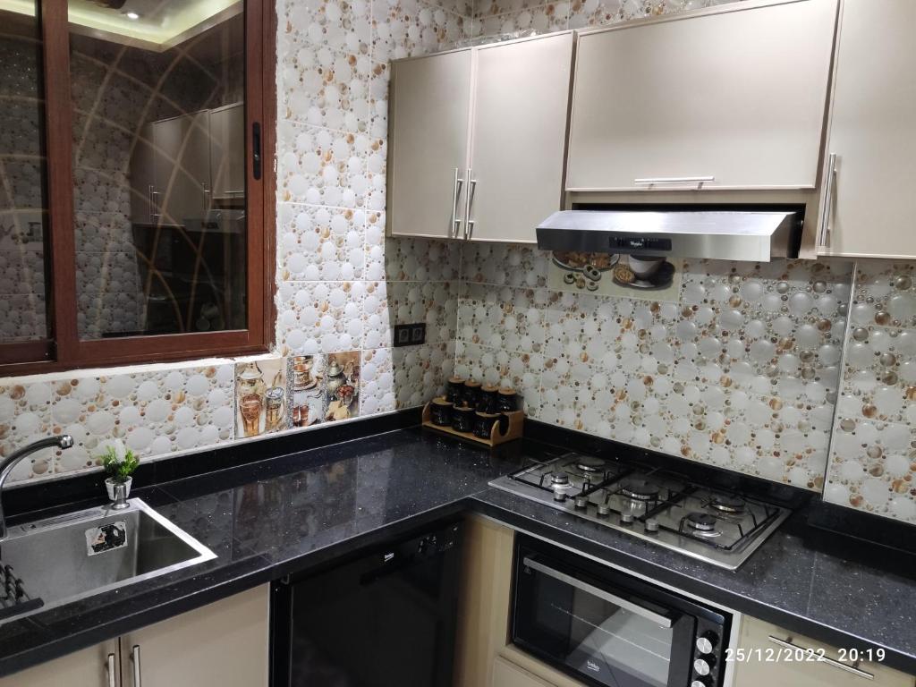 uma cozinha com armários brancos e um forno com placa de fogão em Marrakech golf city em Marrakech