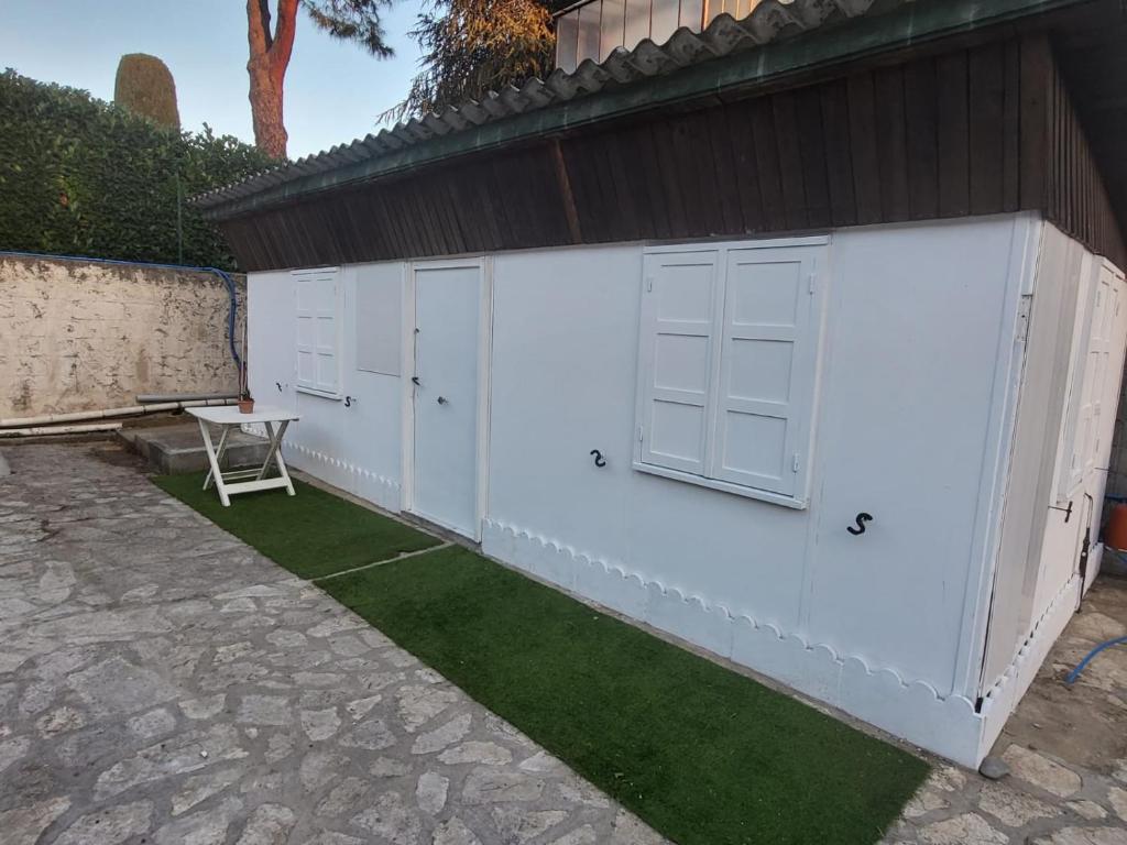 un bâtiment blanc avec deux portes et de l'herbe verte dans l'établissement Cabane pas loin de la plage, à Cagnes-sur-Mer