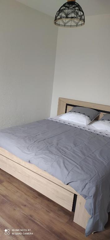 a wooden bed in a bedroom with a light at gite de La place de l'église in Sainte-Mère-Église