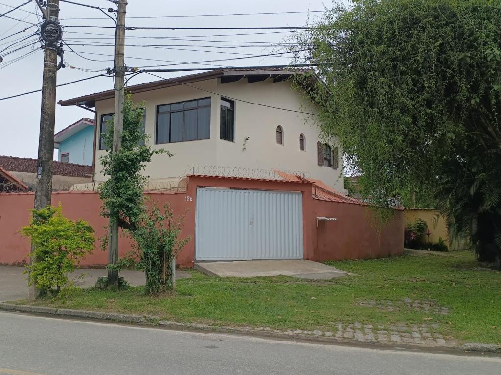 een wit en rood huis met een garage bij Espaço Mar Doce Lar - Praia Indaiá e Riviera in Bertioga