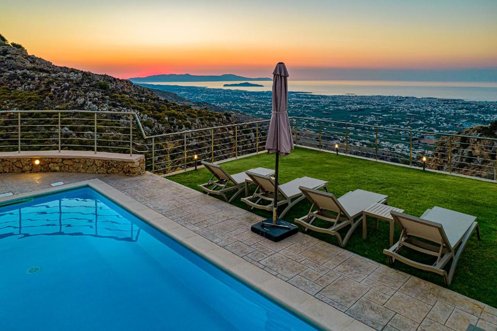 una piscina con sillas y una sombrilla con vistas en Villa Lia Chania with private ecologic pool and amazing view! en La Canea
