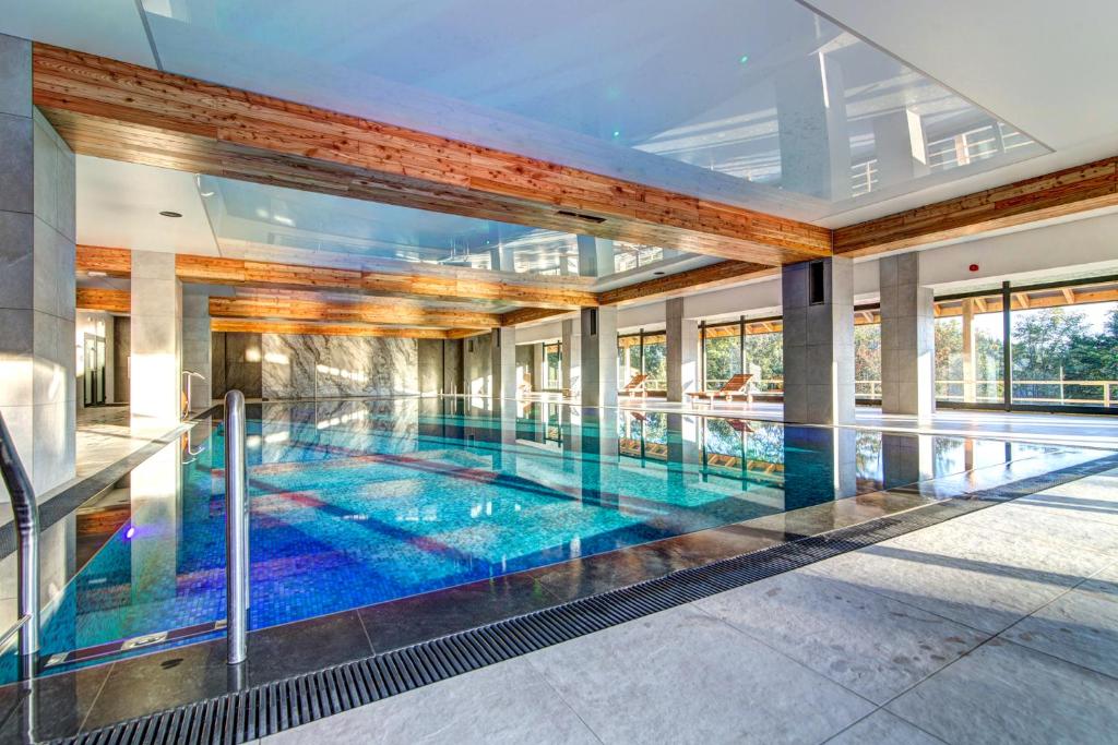 an indoor swimming pool in a building with a large glass wall at Panorama in Krynica Zdrój