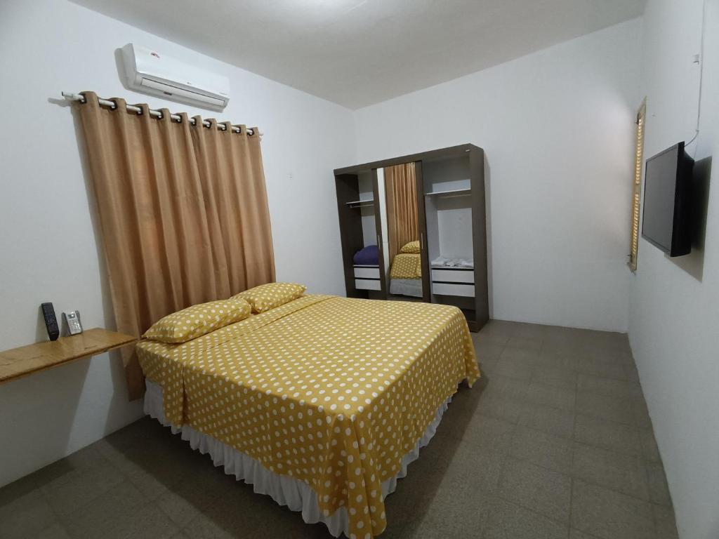 - une chambre avec un lit jaune et un miroir dans l'établissement Bom pra ficar, à Limoeiro do Norte