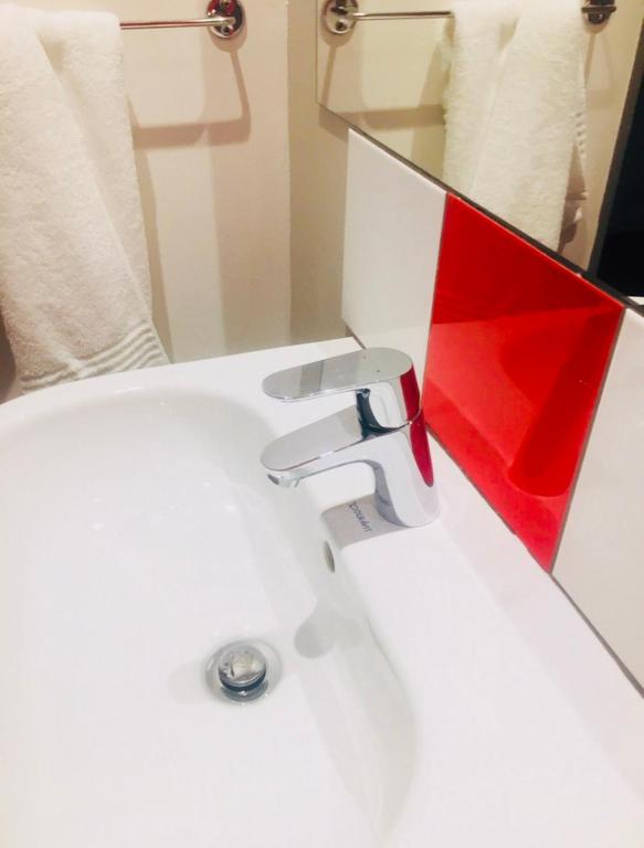 lavabo blanco con espejo rojo en Pammy Guest House, en Richards Bay