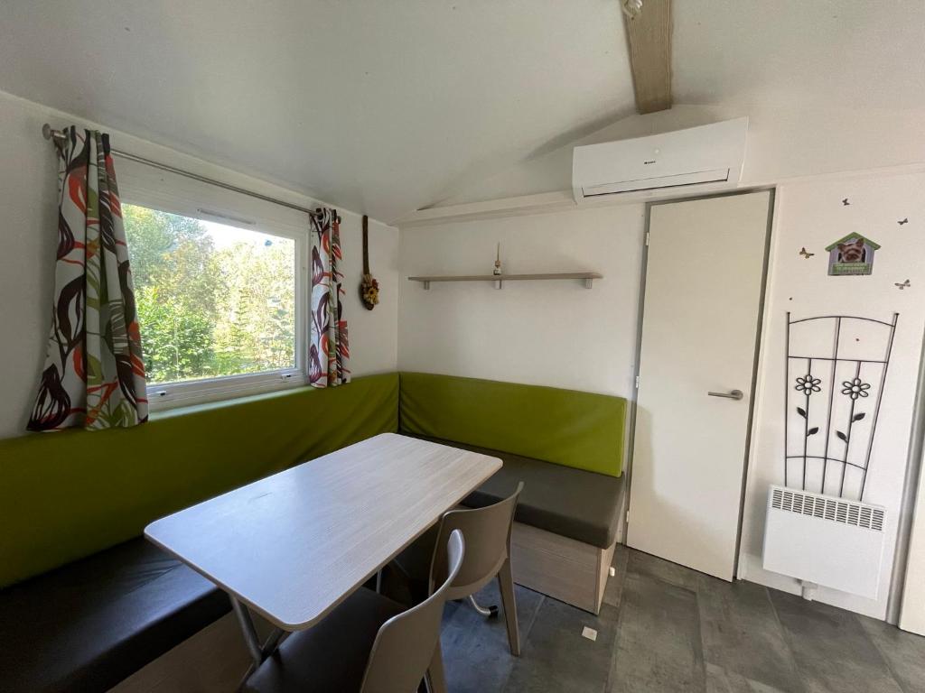 a room with a table and chairs and a window at Mobilehome climatisé avec TV pour 4 à 6 personnes in Boofzheim