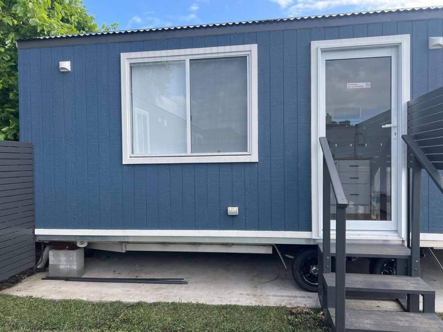 a blue tiny house with a window and a ramp at Sweet Cute blue tiny home with Pool and 2 minute drive to the beach in Wollongong