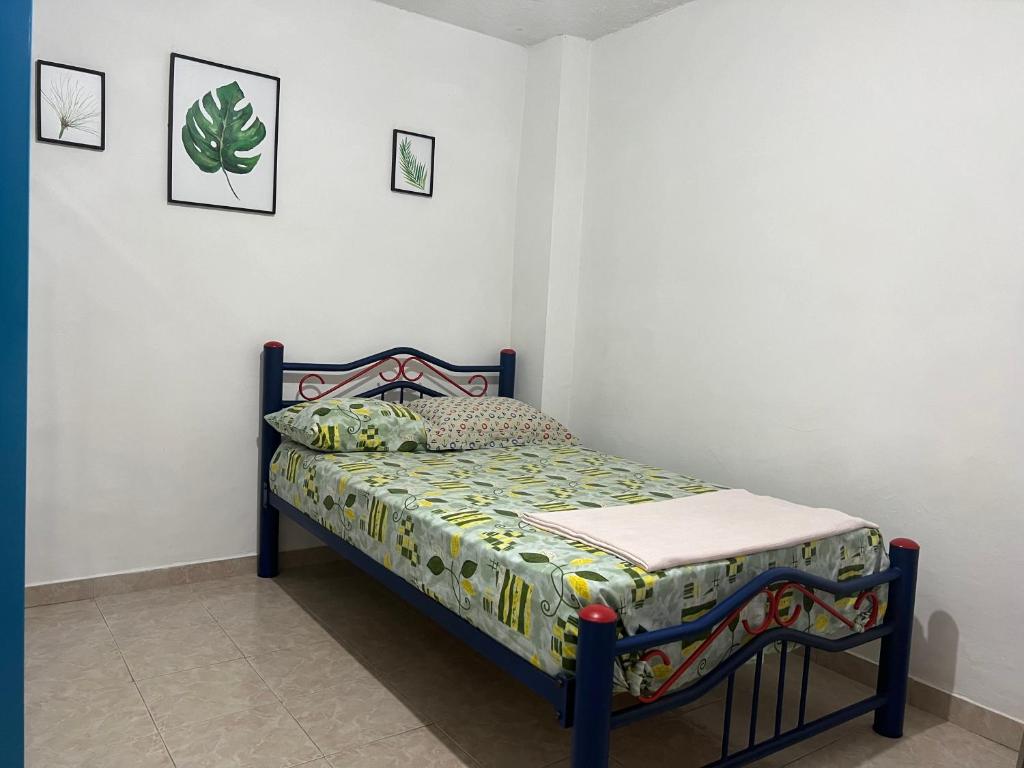 a small bed in a room with two pictures on the wall at Helena Hostel in Cali
