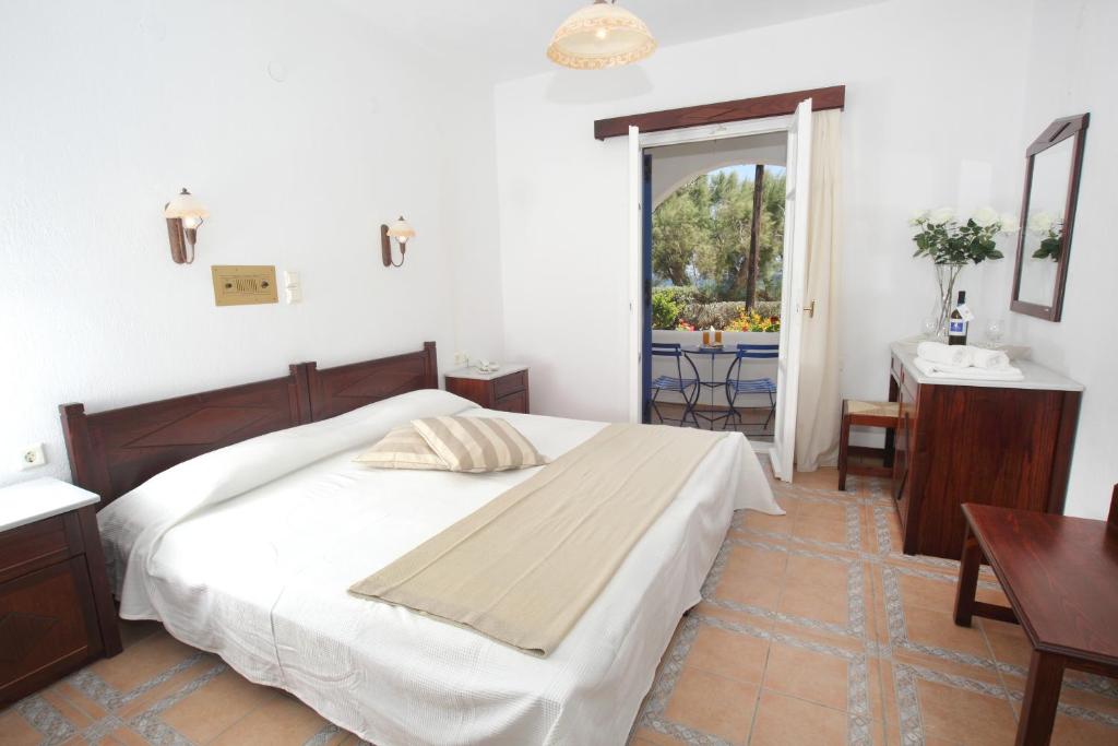Schlafzimmer mit einem Bett, einem Tisch und einem Fenster in der Unterkunft Paros Inn in Logaras