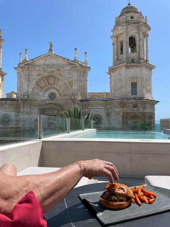 a man is preparing a hamburger on a table in front of a building at Boutique Hotel OLOM - Only Adults recommended in Cádiz