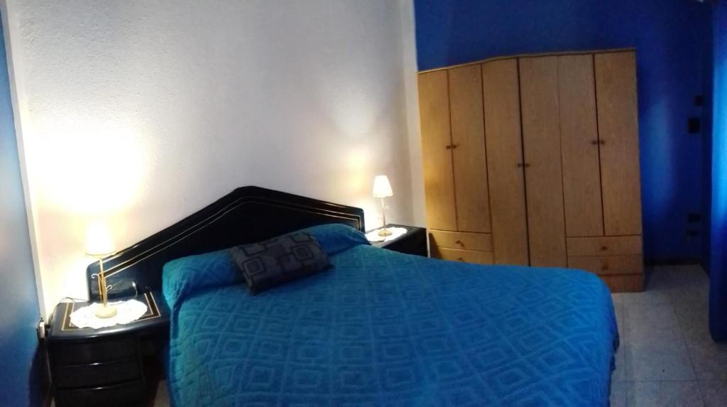 a blue bedroom with a bed and a wooden cabinet at Modernos departamentos PB cerca del centro y del mar in Mar de Ajó