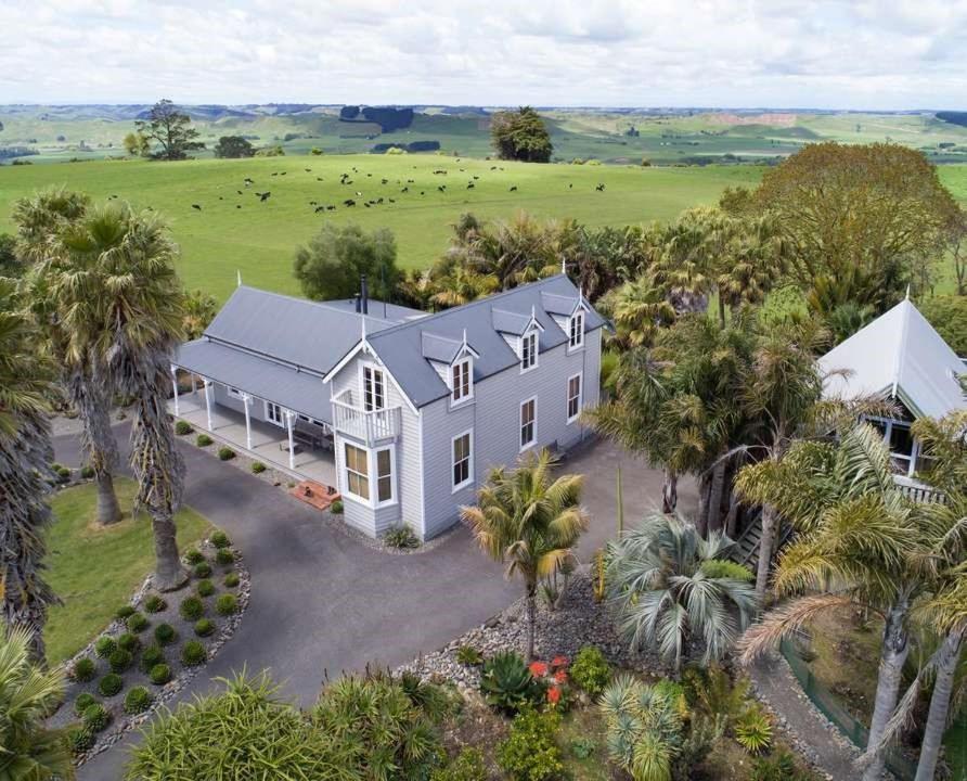- une vue aérienne sur une grande maison blanche avec des palmiers dans l'établissement Headlands Estate, à Whanganui