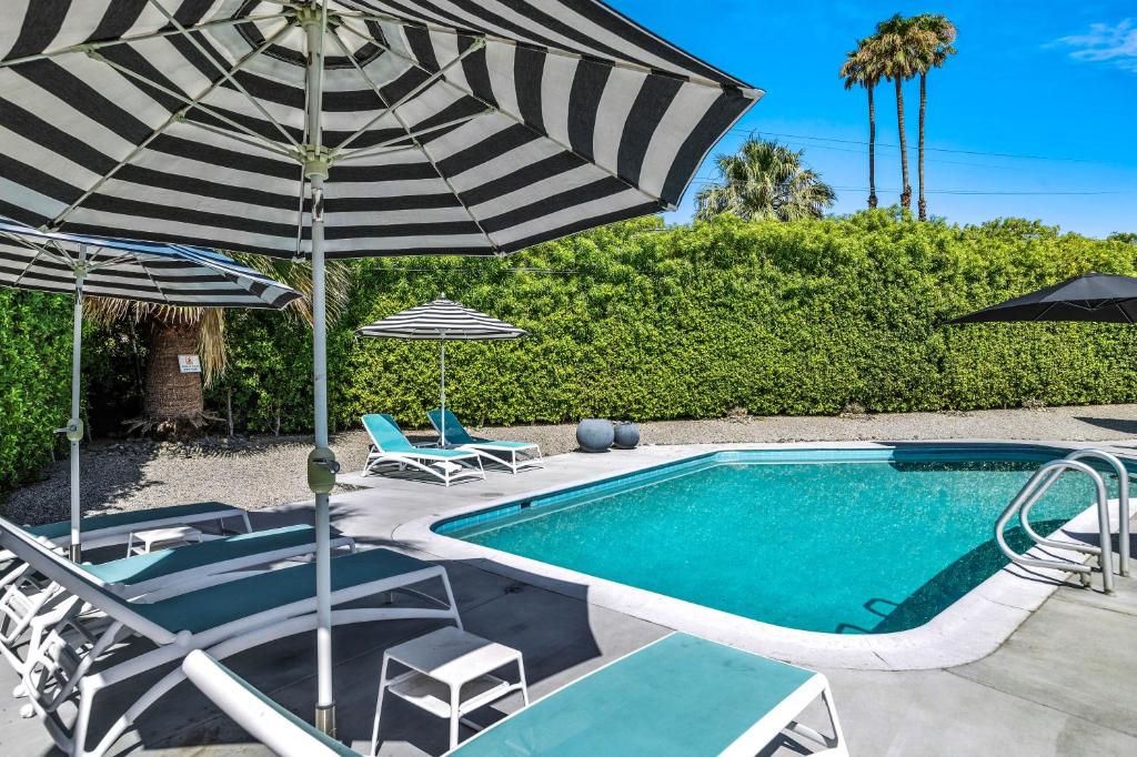 een zwembad met stoelen en een parasol en een zwembad bij Bright & Harmonious Oasis - A Ryson Property in Palm Springs