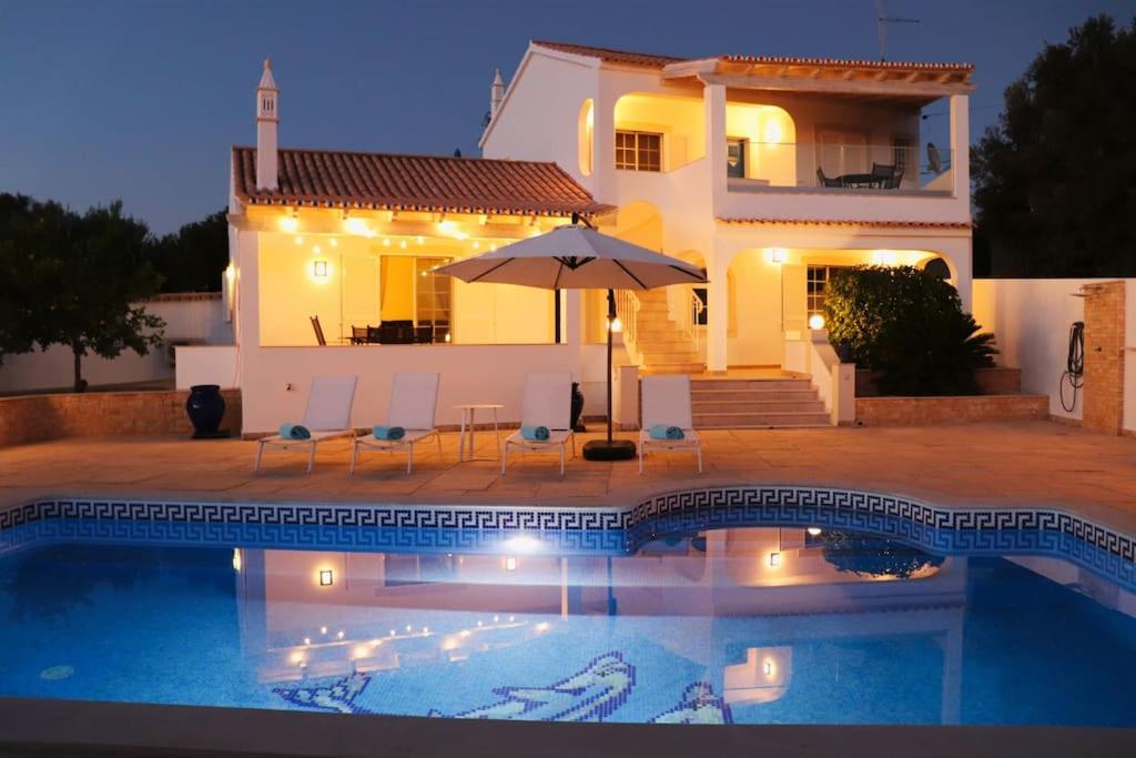 a villa with a swimming pool in front of a house at Villa with pool and sea view with two independent floors in Faro