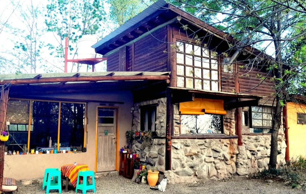 Una casa de piedra con dos taburetes azules delante de ella. en Casa Sol y Luna, en Villa General Belgrano