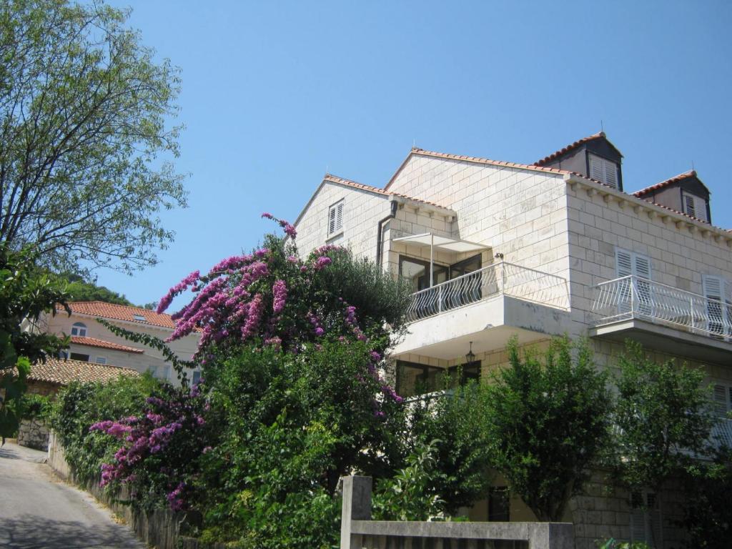 un edificio blanco con flores púrpuras delante de él en Apartments and Rooms Artemida, en Dubrovnik