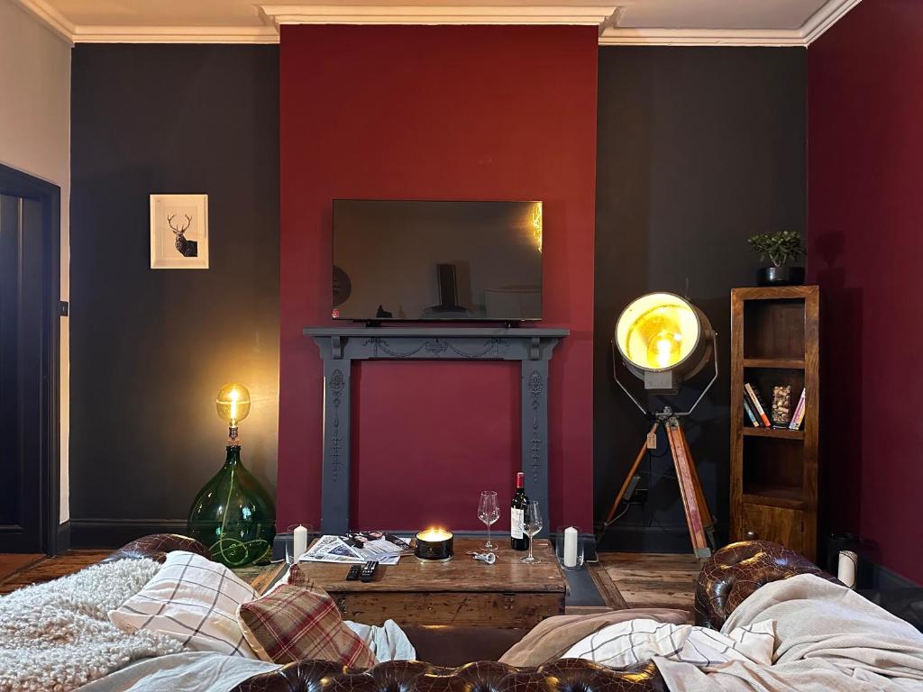 a living room with a red wall and a mirror at The Bolt Hole in Stratford-upon-Avon