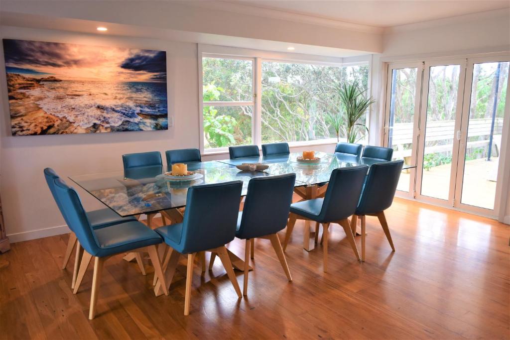una sala da pranzo con tavolo in vetro e sedie blu di Kai Iwi Lakes Resort a Kaihu