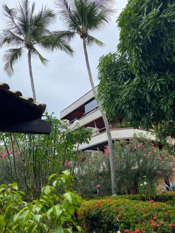 un edificio con palmeras y flores en un jardín en Estúdio Village Ilha dos Corais en Vera Cruz de Itaparica