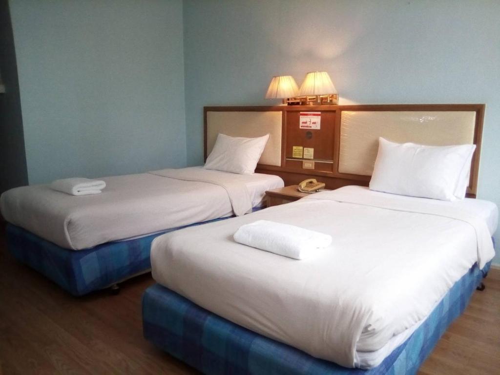 two beds in a hotel room with white sheets at ปิดชั่วคราว ชิดลม in Makkasan