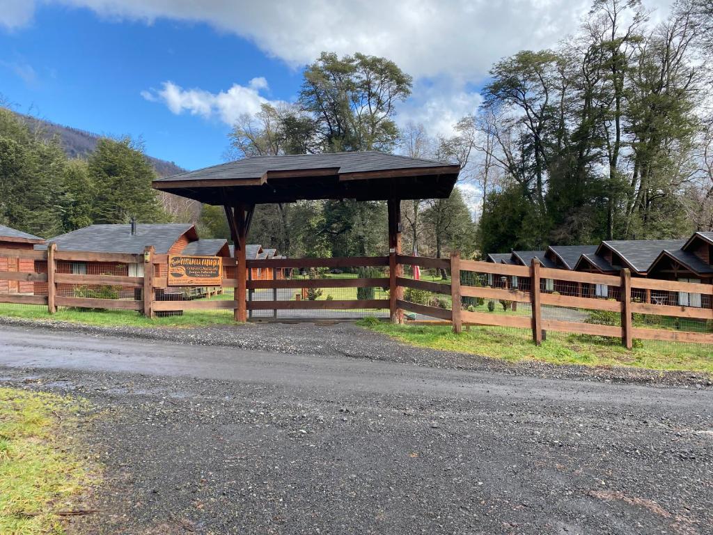 a wooden fence with a wooden pavilion next to a field at Portal Costanera Caburgua in Caburgua