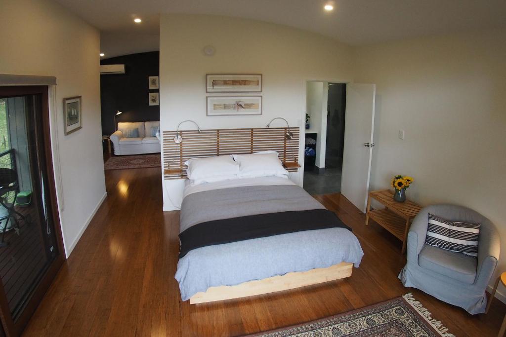a bedroom with a large bed and a chair in it at Kaalba in Maleny