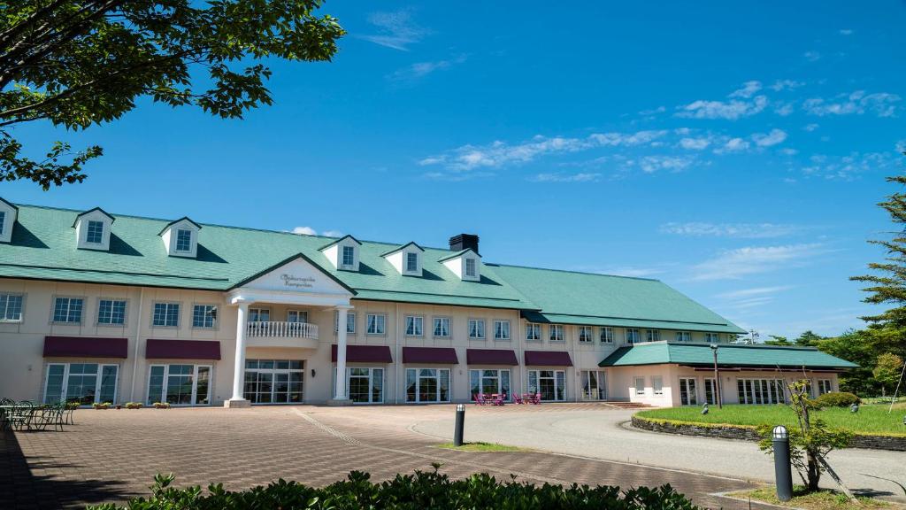 a large white building with a green roof at Satoyama Auberge & Hot Spring Wellness Spa Sakuragaike Kurgarden in Nanto