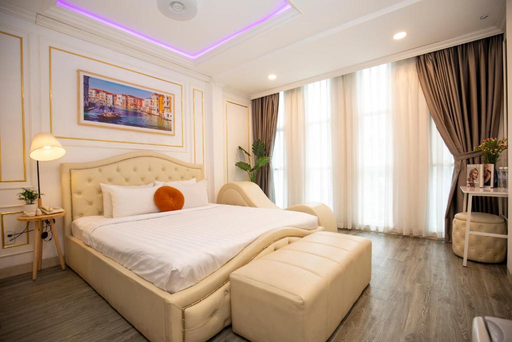 a bedroom with a large white bed and a couch at Quy Hung Hotel Central in Ho Chi Minh City