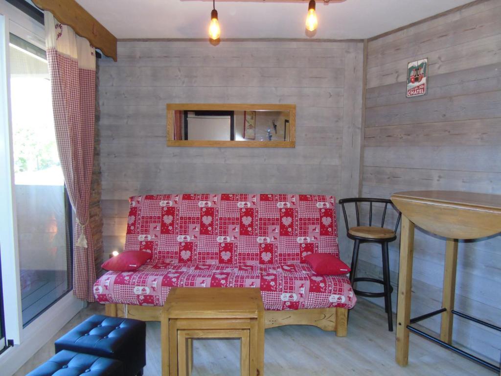 a room with a red bed and a table at Appartement Châtel, 2 pièces, 4 personnes - FR-1-198-114 in Châtel