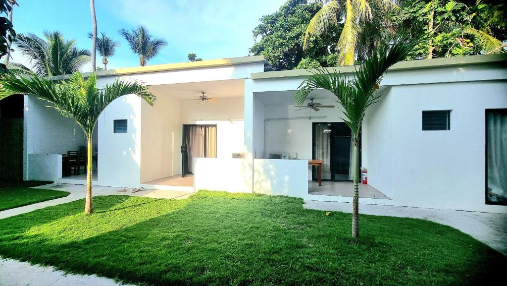 una casa blanca con dos palmeras en el patio en Tiki Bantayan Cebu Tourist Inn Inc, en Pooc