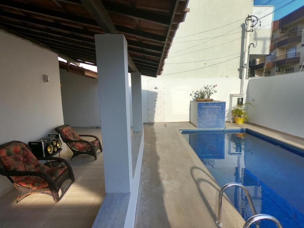a swimming pool with two chairs next to a house at Luxo nas Ondas: Casa de Praia de Alto Padrão in São João da Barra