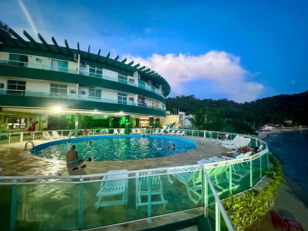 un hotel con una piscina junto al agua en Angra Inn Praia Grande, en Angra dos Reis