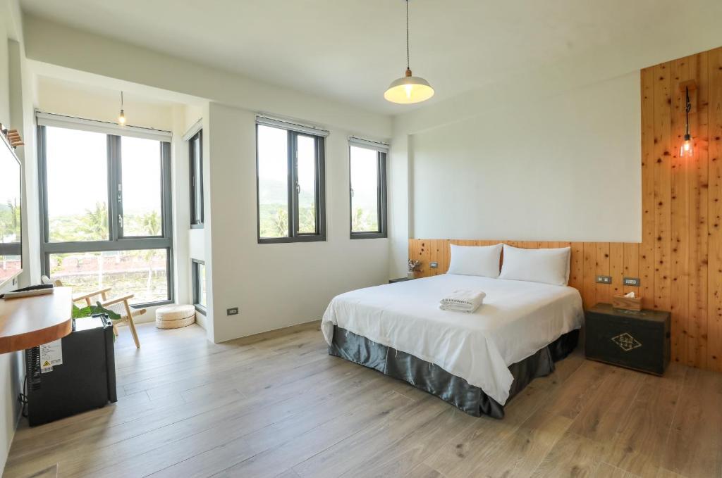 a bedroom with a large white bed and some windows at Mountains Inn in Hengchun South Gate