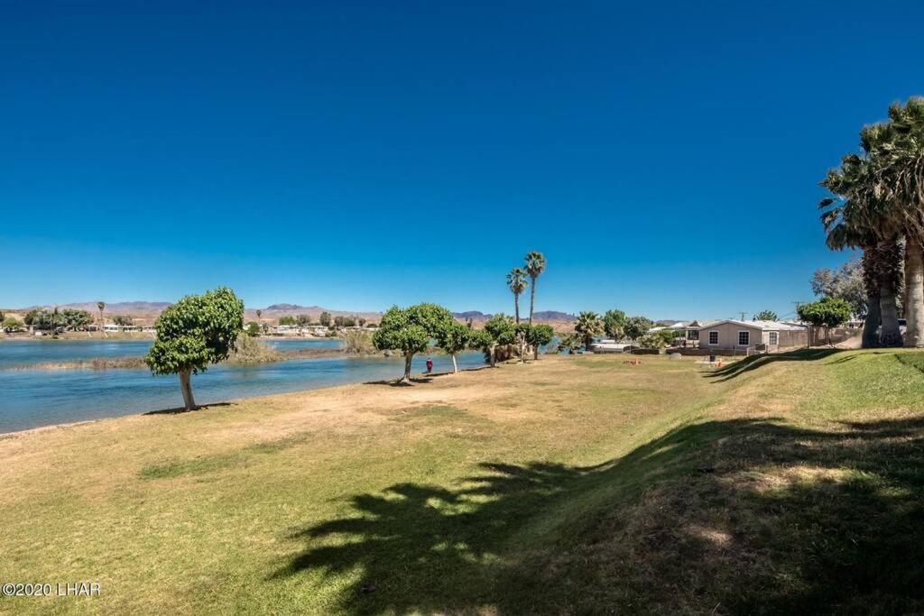 a park next to a river with palm trees at Lower River Retreat in Parker