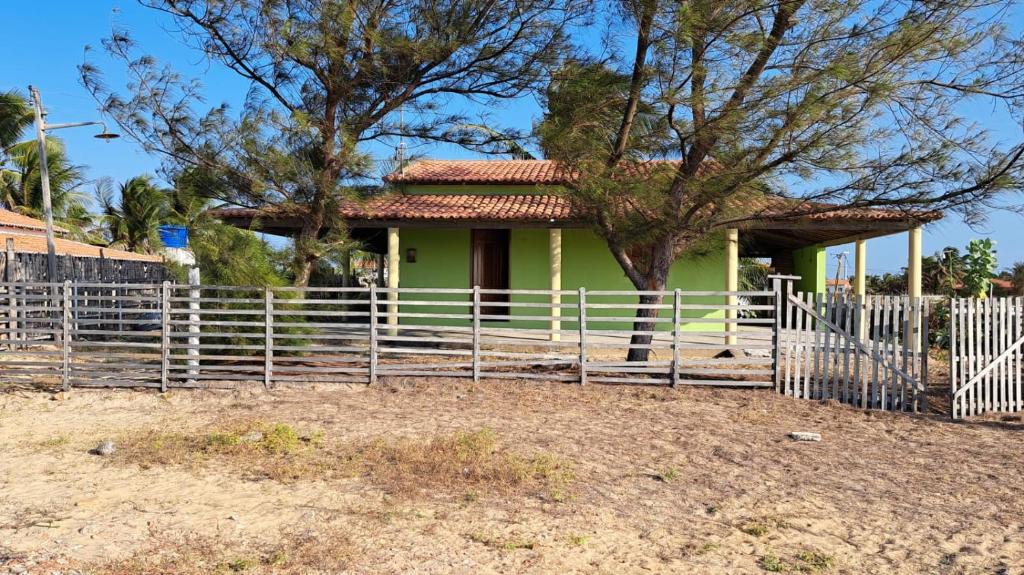 une maison verte avec une clôture devant elle dans l'établissement CASA DE PRAIA DA PEDRA DO SAL, à Parnaíba