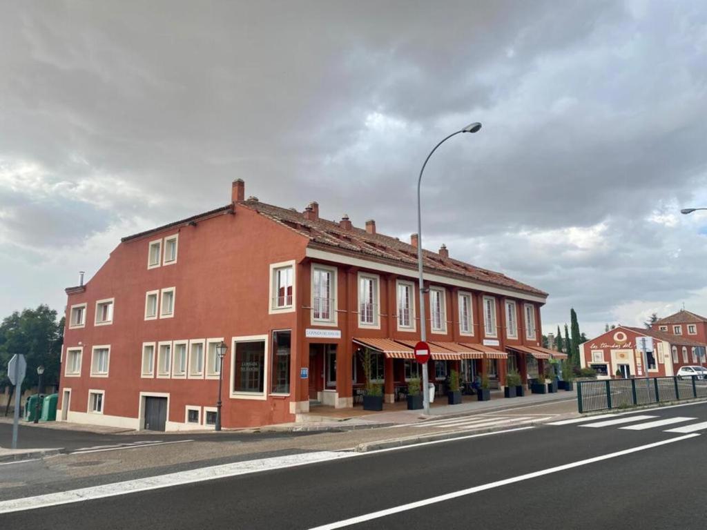 duży czerwony budynek na ulicy z światłem ulicznym w obiekcie La Posada del Rancho w mieście Segovia