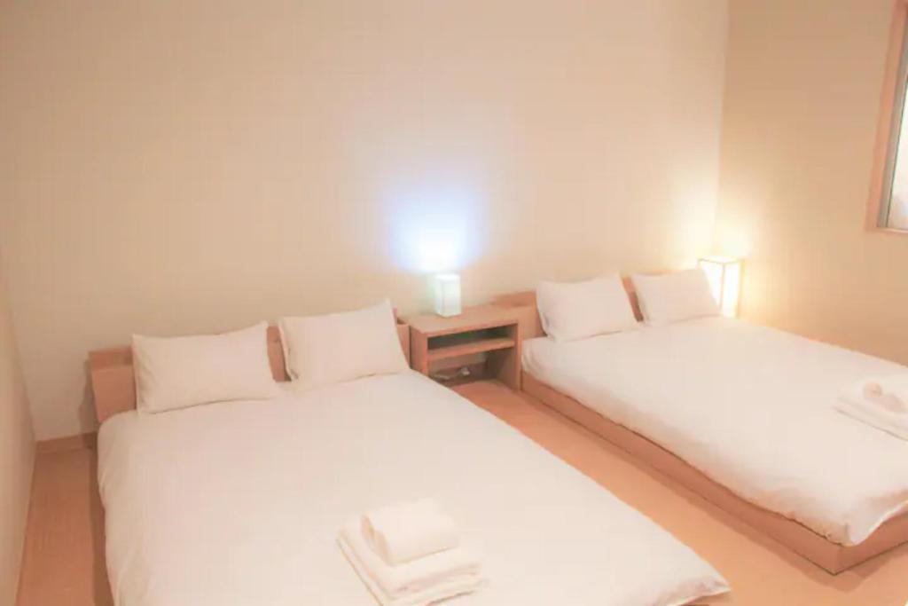 two beds in a room with white sheets at Fortune house 步行直達大阪京瓷巨蛋 直達梅田 桜川4丁目 in Osaka