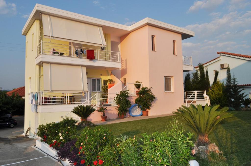 a pink house with a balcony and some plants at Olympion Village Studios in Zacharo