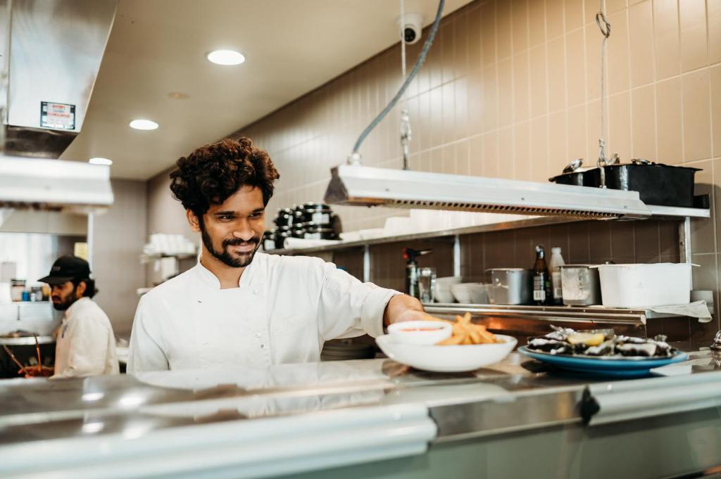 a man holding a plate of food in a kitchen at Ceduna Foreshore Hotel Motel in Ceduna