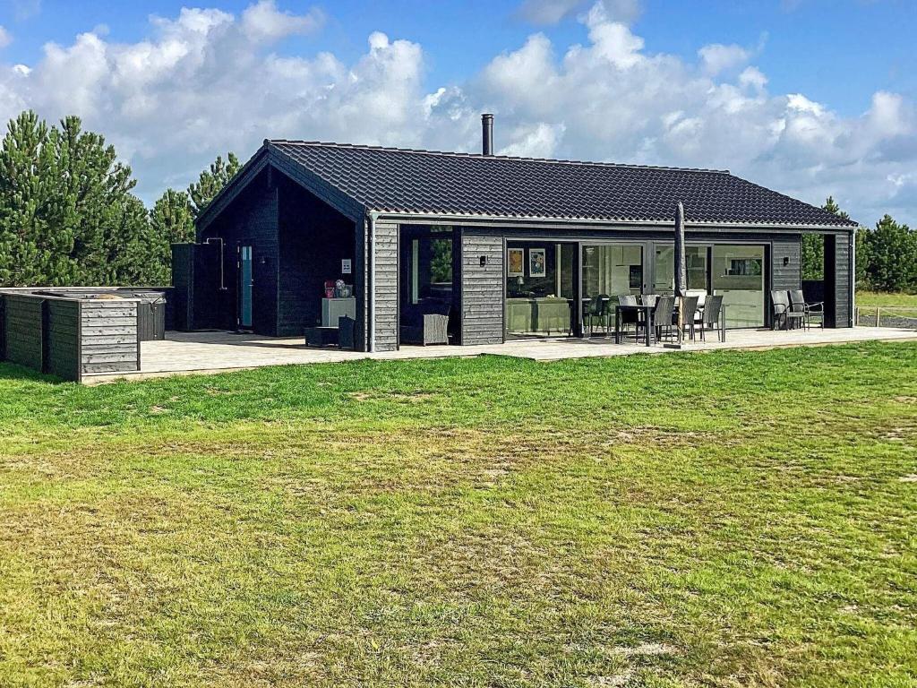 een klein zwart huis met een grasveld bij Holiday home Væggerløse CCXVII in Bøtø By