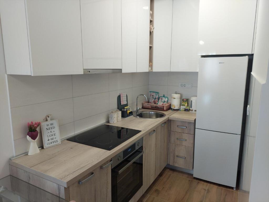 a kitchen with white cabinets and a sink and a refrigerator at K2-SistersApartment in Podgorica