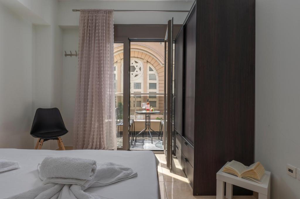 een slaapkamer met een bed en een balkon met een tafel bij Sigrou 44 in Thessaloniki